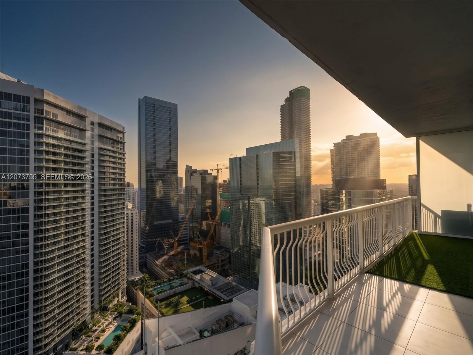 Covered balcony featuring white metal railings, light-toned floor tiling, and integrated synthetic turf surfacing