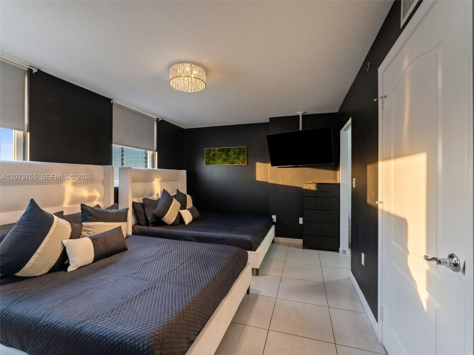 Ceramic tile flooring, crown molding-accented ceiling, crystal-style flush mount lighting, and custom roller shades