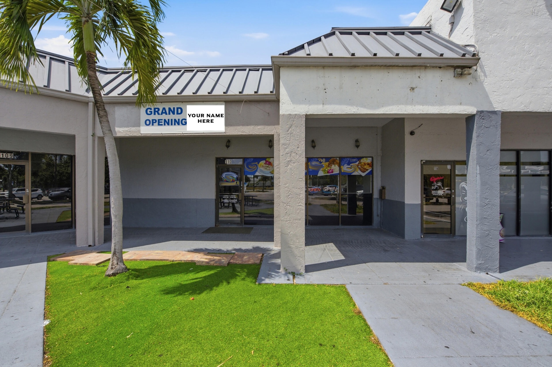 Commercial storefront exterior featuring a metal roof, concrete-finished facade, covered walkway, and full-height glass entry doors