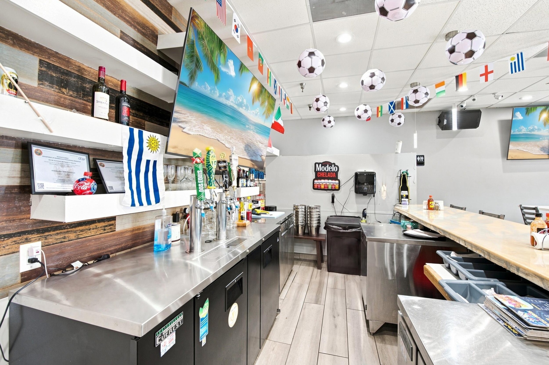 Bar area featuring stainless steel under-counter refrigeration, metal draft beer towers, wood-finish wall paneling, built-in shelving, and a bar-heigh