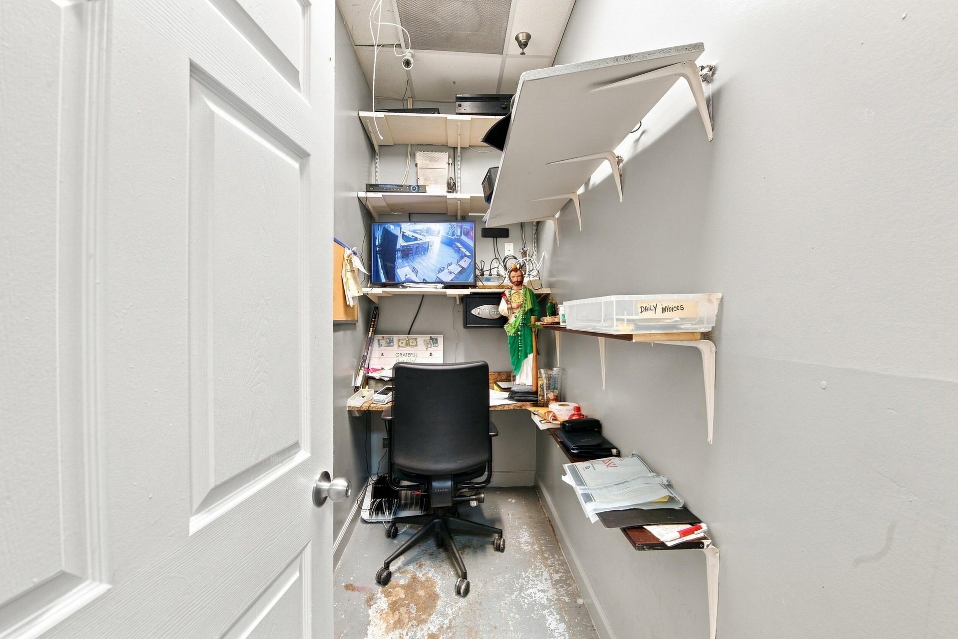 Storage space featuring multi-level white wall-mounted shelving and a built-in work surface