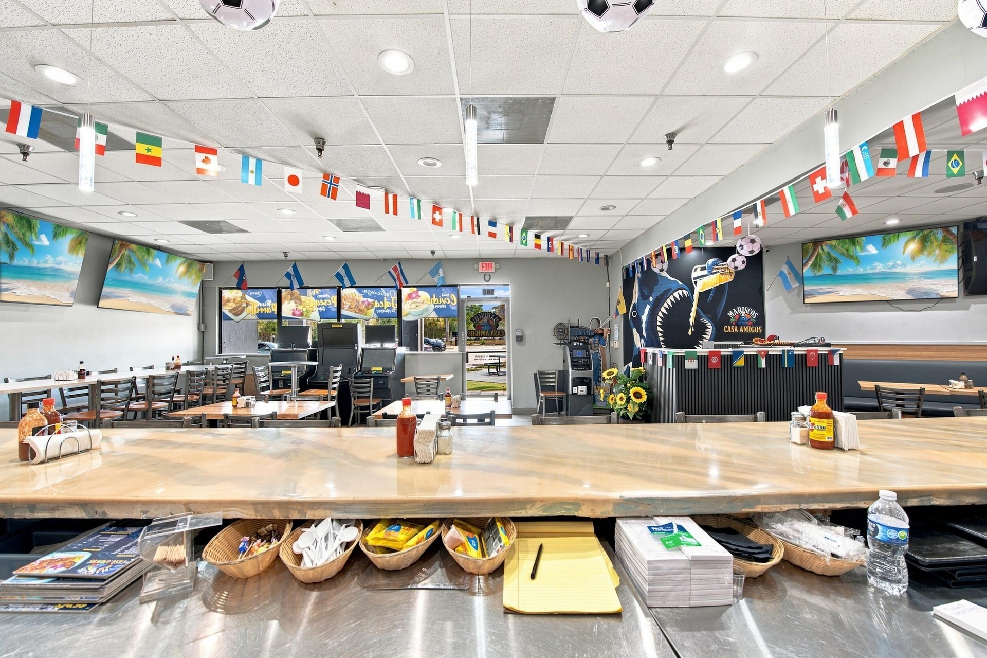 Spacious interior featuring a large service counter with a neutral-toned stone surface, recessed ceiling lighting, a dedicated bar area with structure