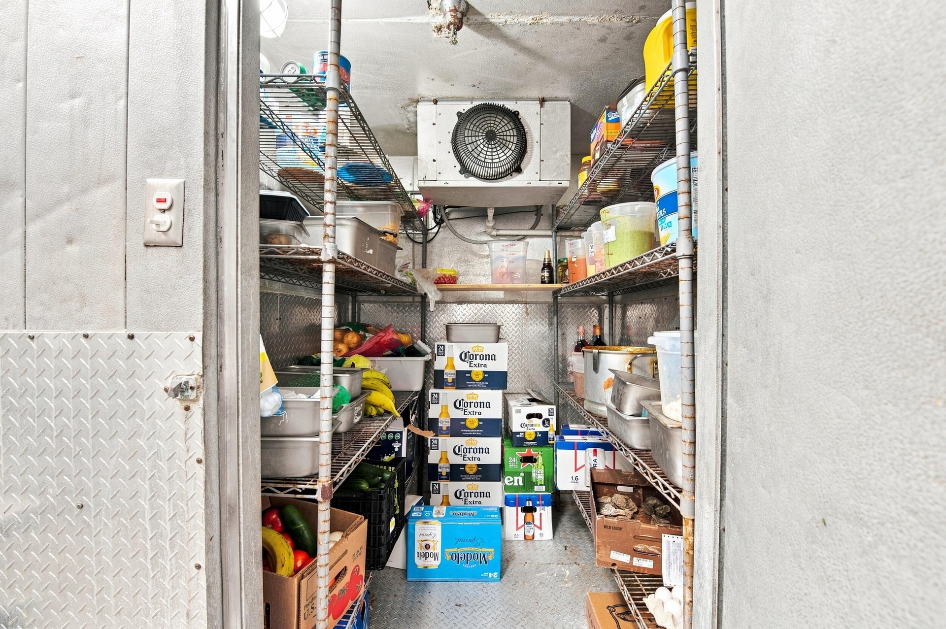 Commercial walk-in cooler featuring diamond plate metal paneling, industrial-grade cooling unit, and multi-tier wire shelving