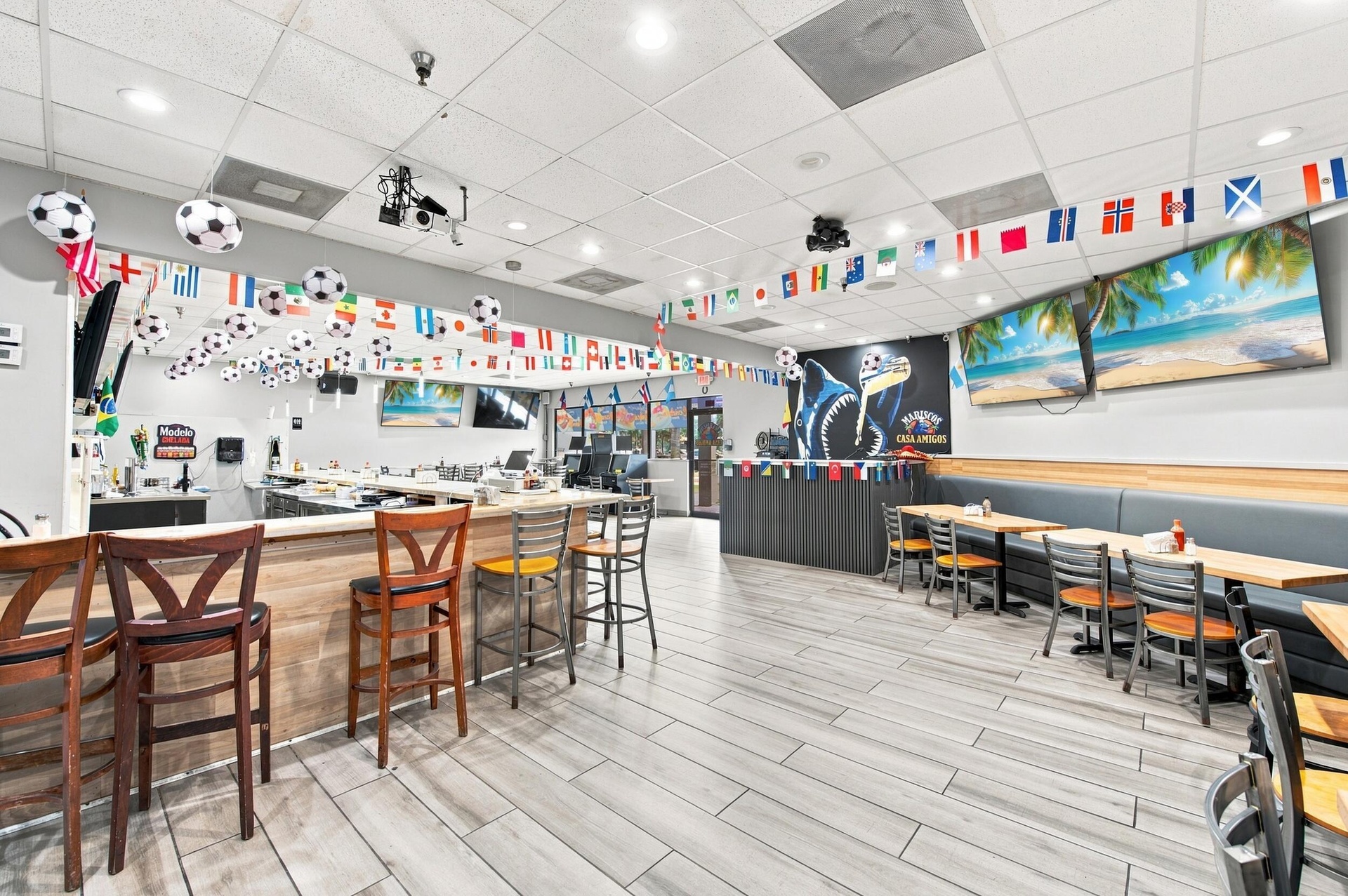 Spacious interior featuring wood-finish tile flooring, recessed ceiling lighting, a built-in bar counter, and integrated wall-mounted counter seating