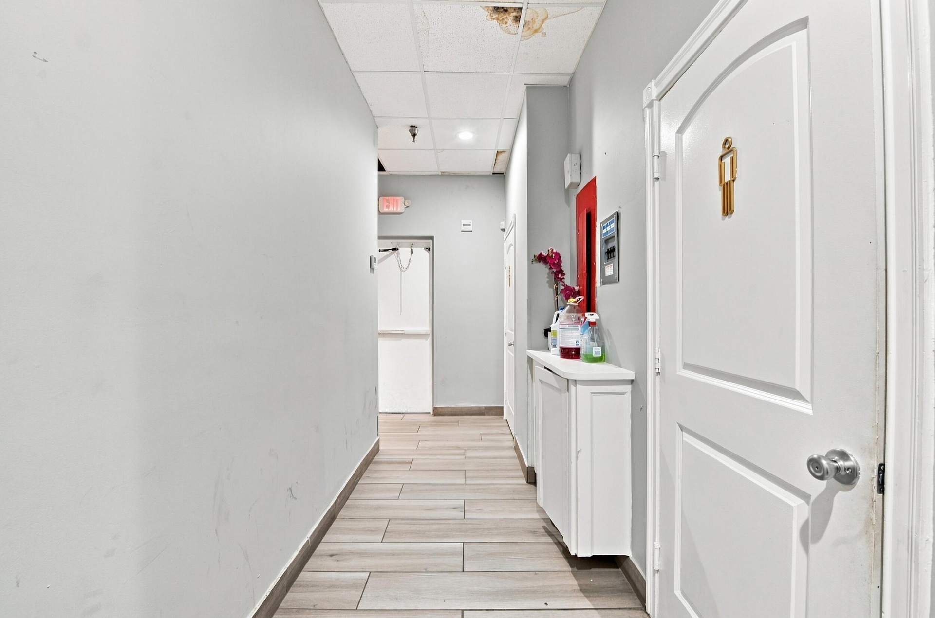 Hallway featuring wood-finish tile flooring, recessed ceiling panels, and white-painted interior doors