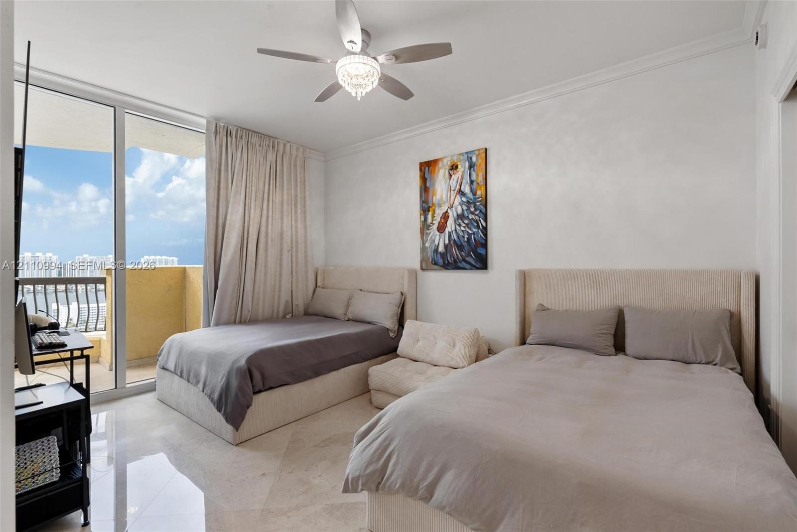 Floor-to-ceiling glass sliding doors opening to a balcony, polished stone flooring, crown molding, and a central ceiling fan with an integrated light 