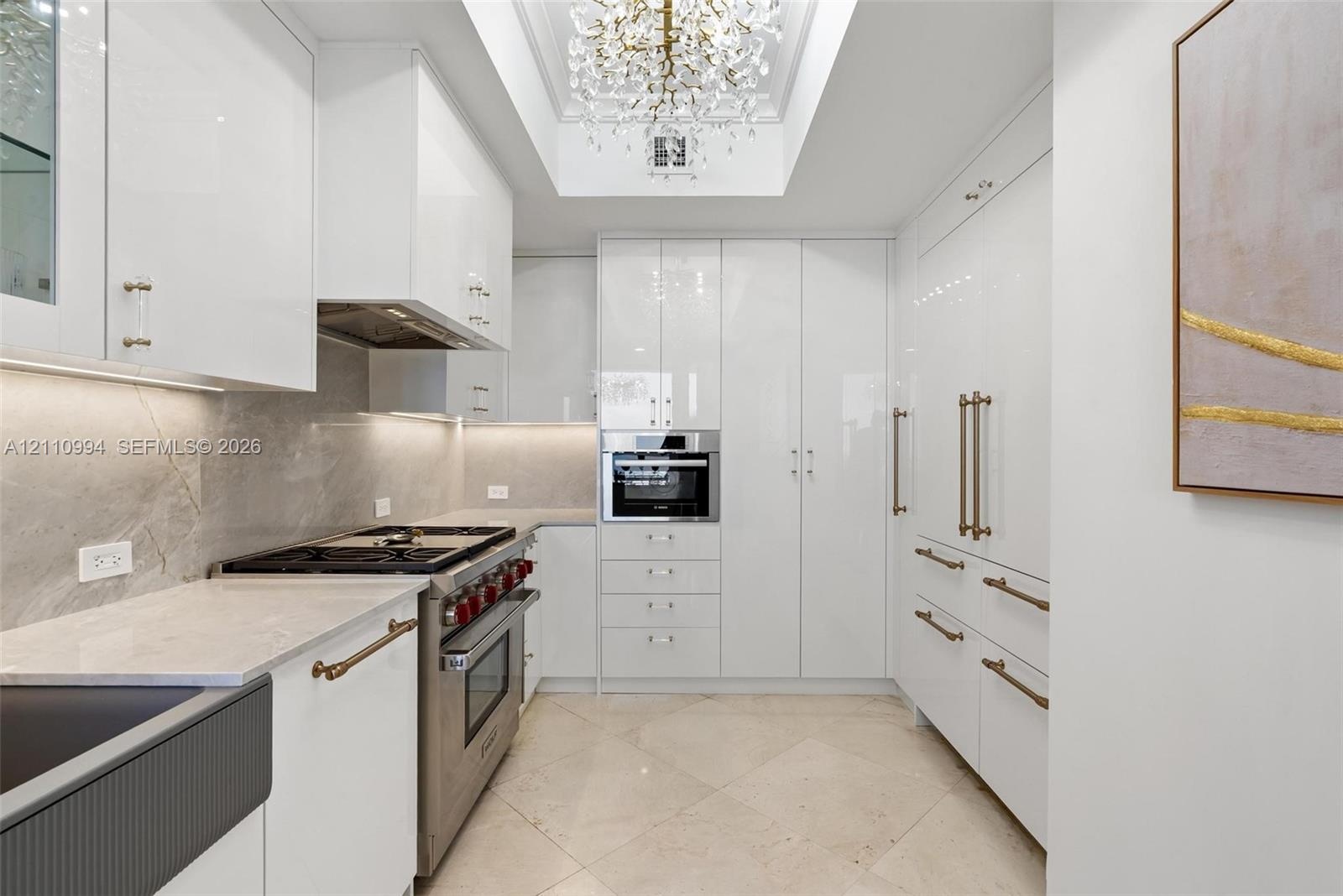 Gourmet kitchen featuring high-gloss cabinetry, stone-finish countertops, tile flooring, stainless steel professional-grade range, and a coffered ceil