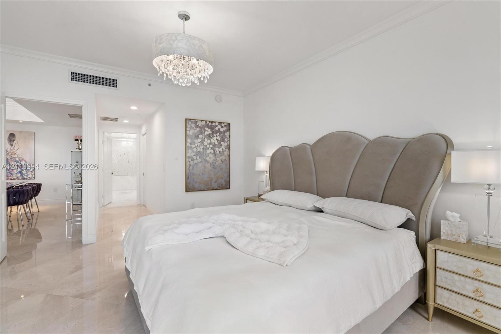 Polished stone flooring, crown molding, and crystal-accented drum pendant lighting