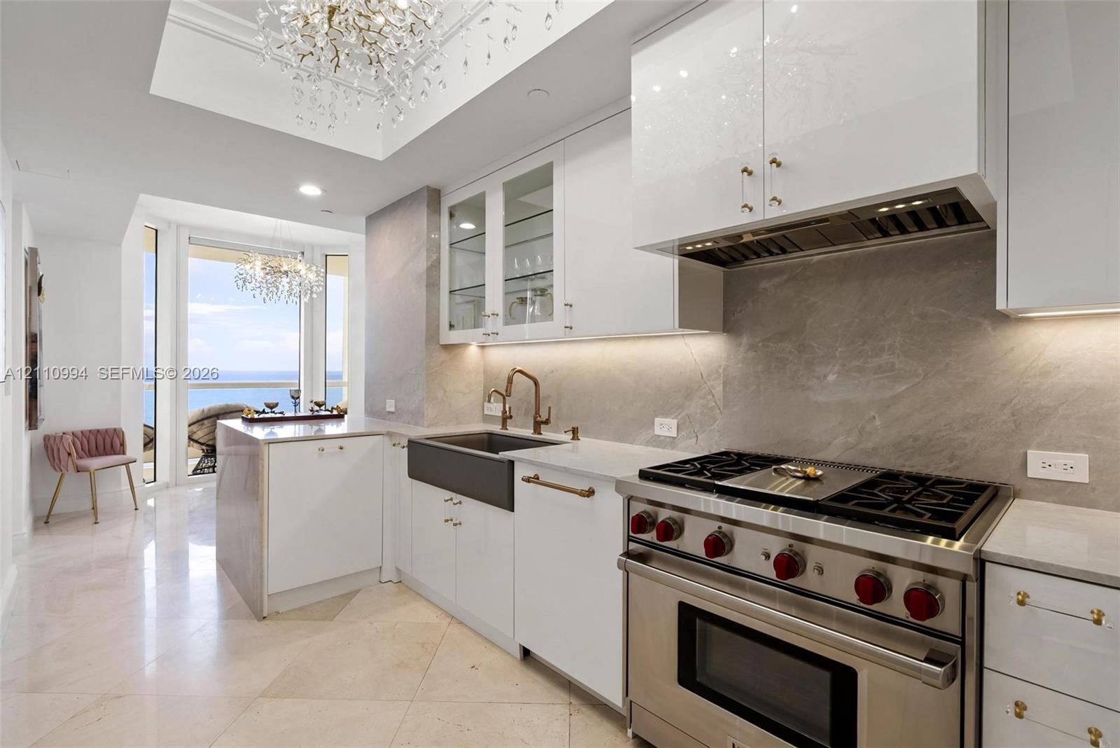Chef’s kitchen featuring custom white cabinetry, stone slab backsplash, farmhouse-style apron sink, professional-grade stainless steel range, and ston