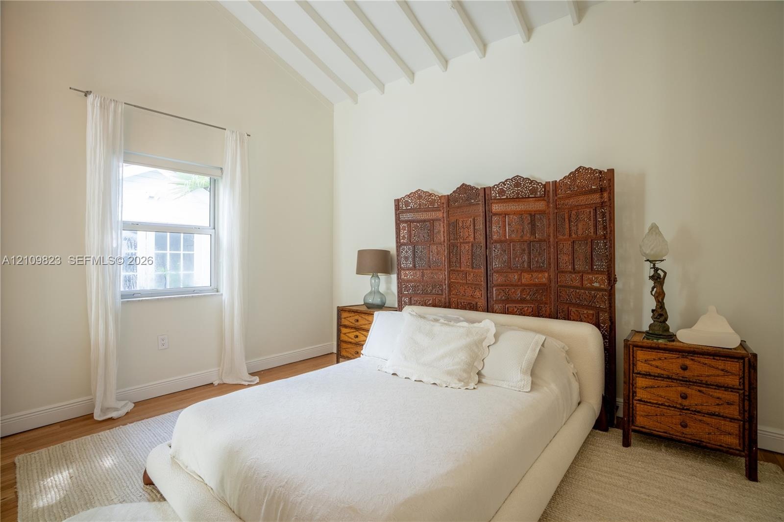 Vaulted ceiling with exposed white beams and wood-finish flooring