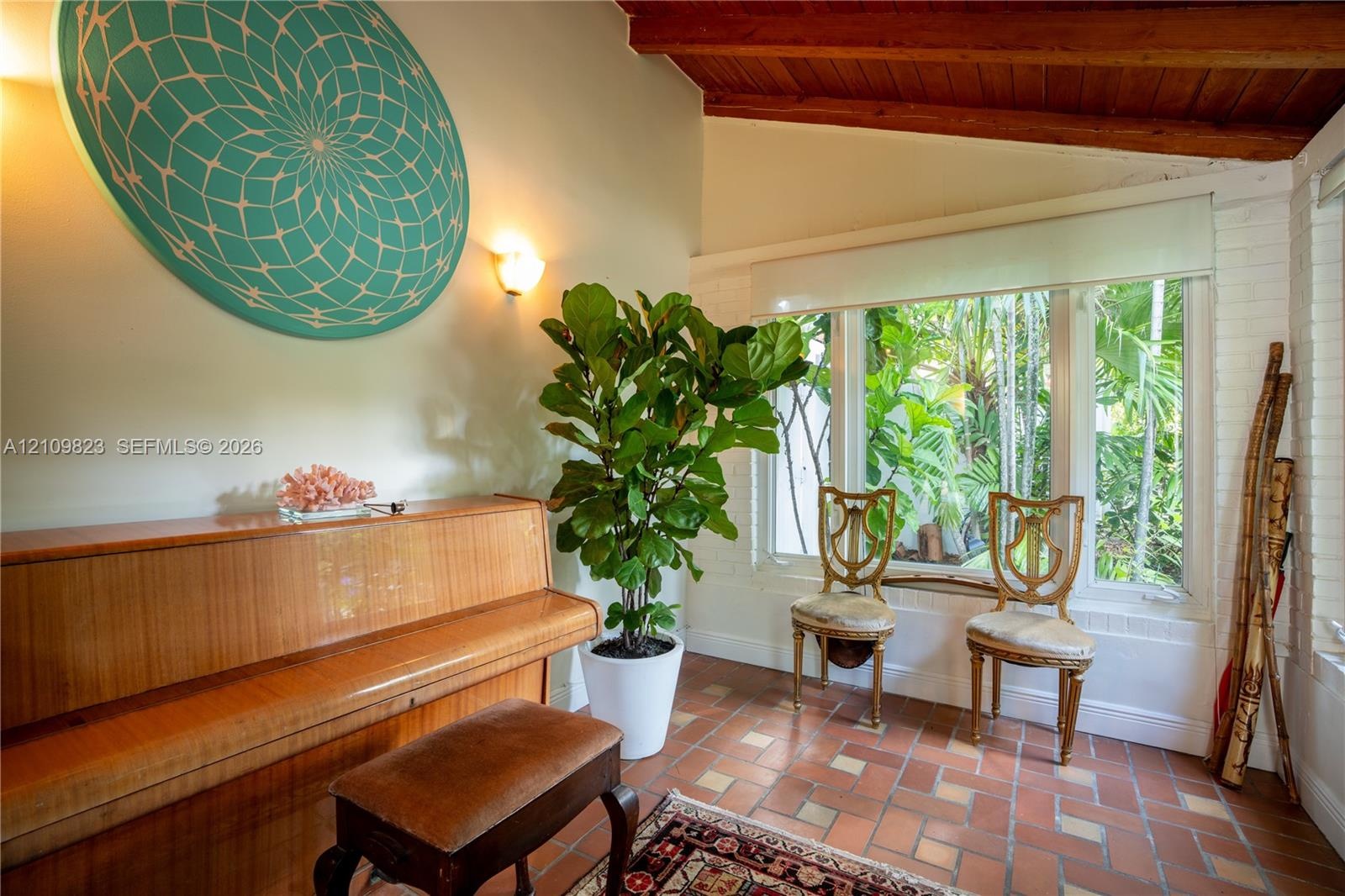 Exposed wooden ceiling beams, large picture windows, brick-style floor tiles, and painted white brick wall accents