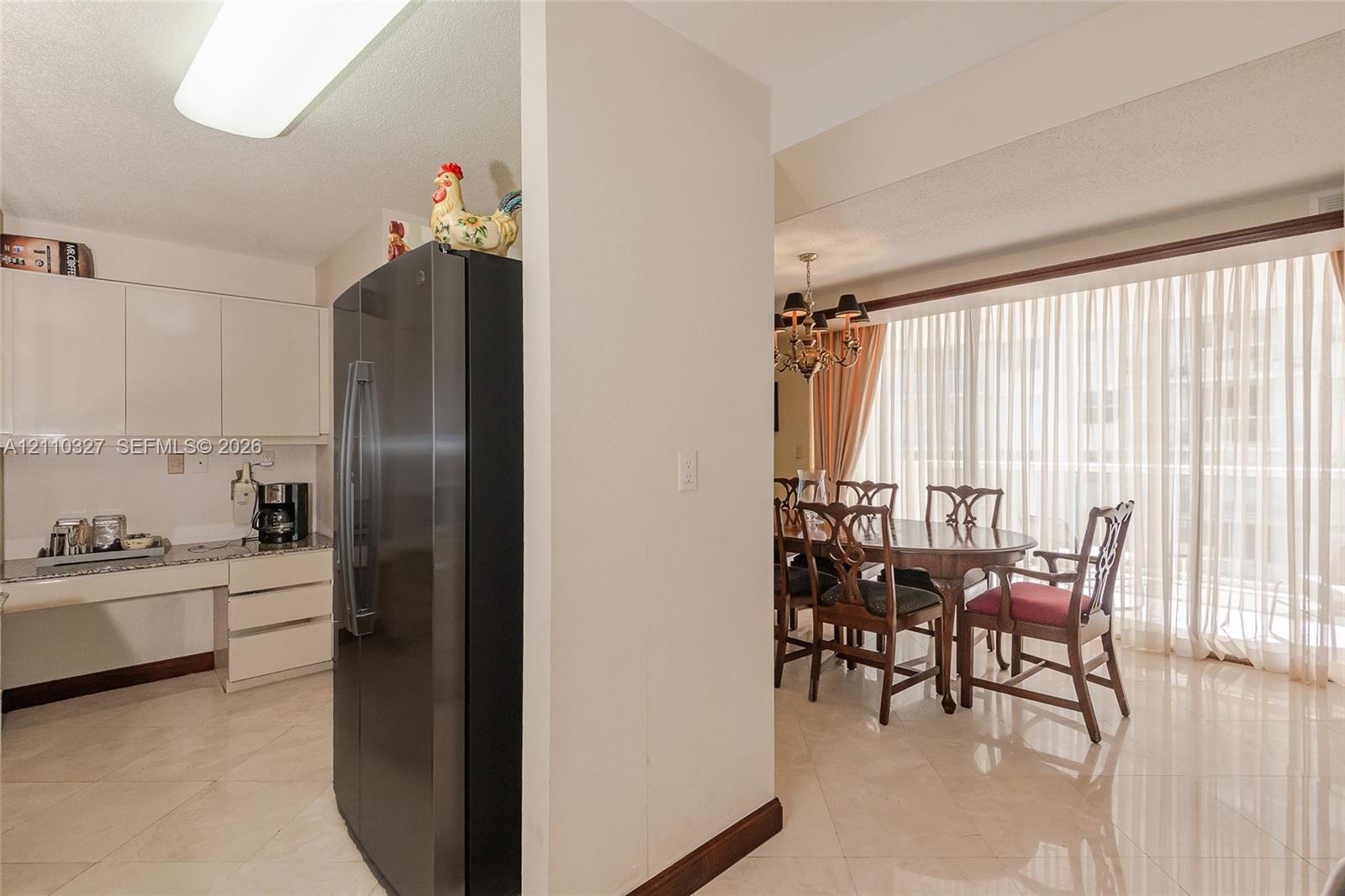 Floor-to-ceiling sliding glass doors opening to a private balcony, wood-finish flooring, and ocean backdrop
