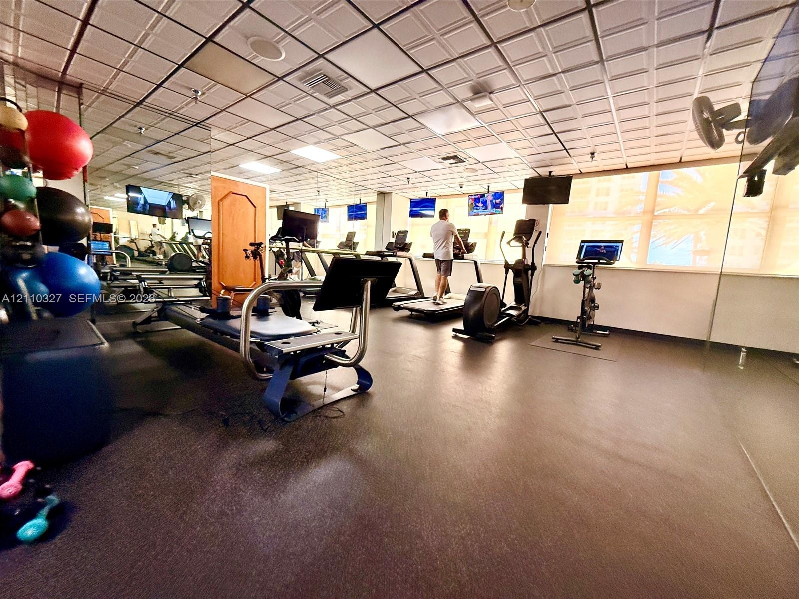 Open-concept room featuring high ceilings with recessed lighting, large windows, and durable flooring