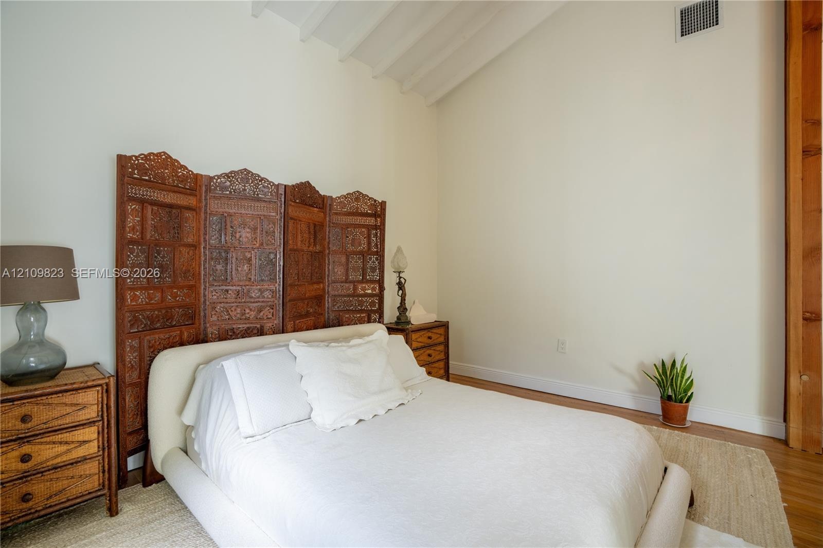 Vaulted ceiling, wood-finish flooring, and natural wood-toned vertical structural pillar