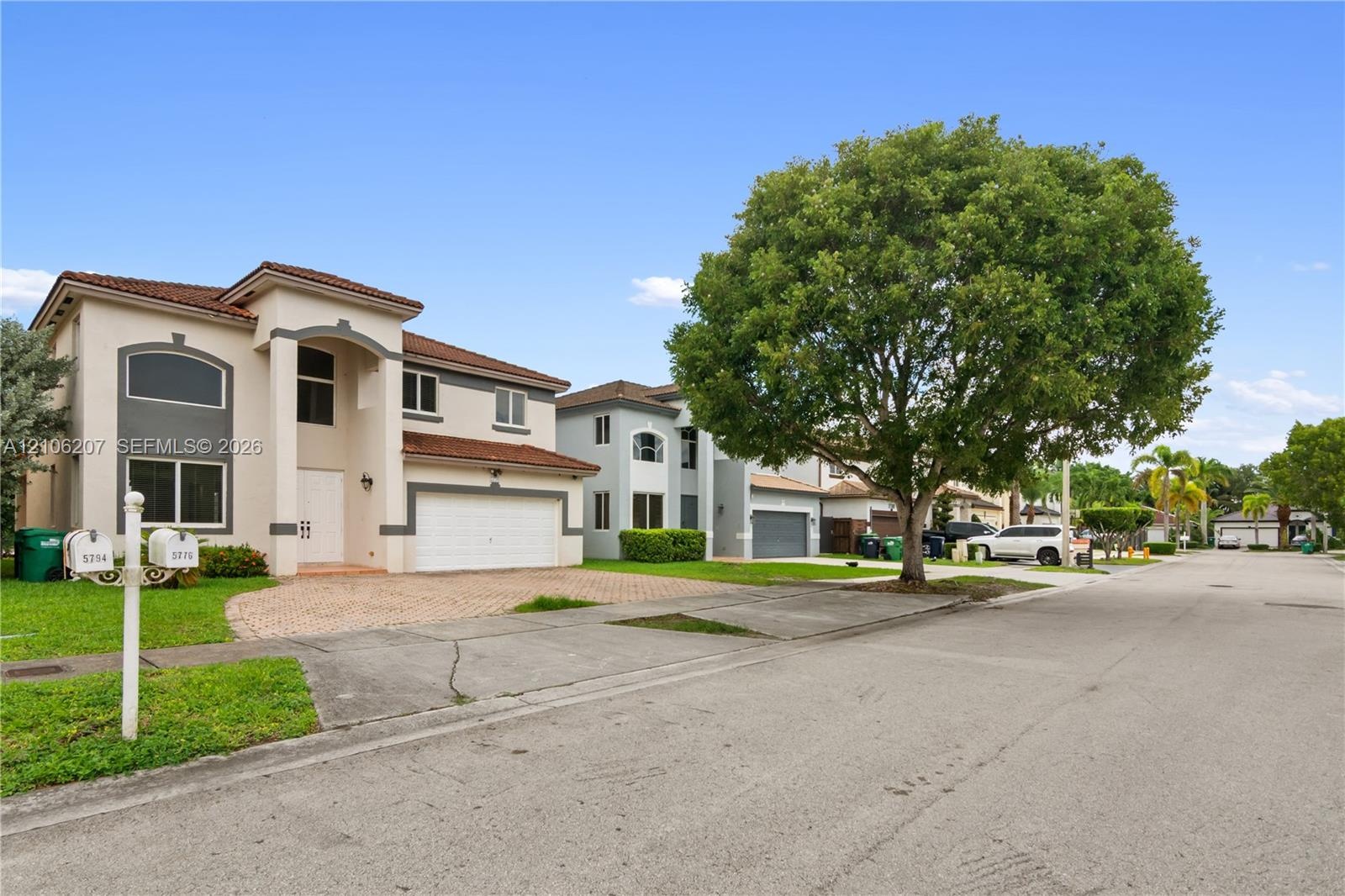 Stucco exterior featuring a dual-level arched entryway, barrel-tile roof, and brick-paver driveway