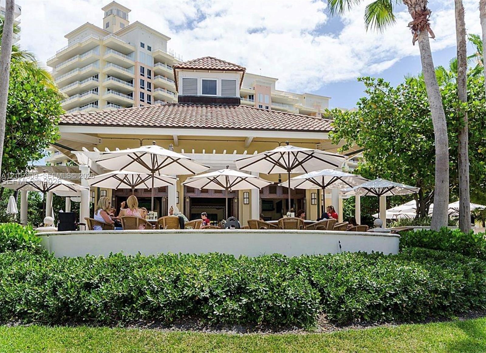 Outdoor pavilion featuring a tile roof, structural pergola, masonry perimeter wall, and mature landscaping
