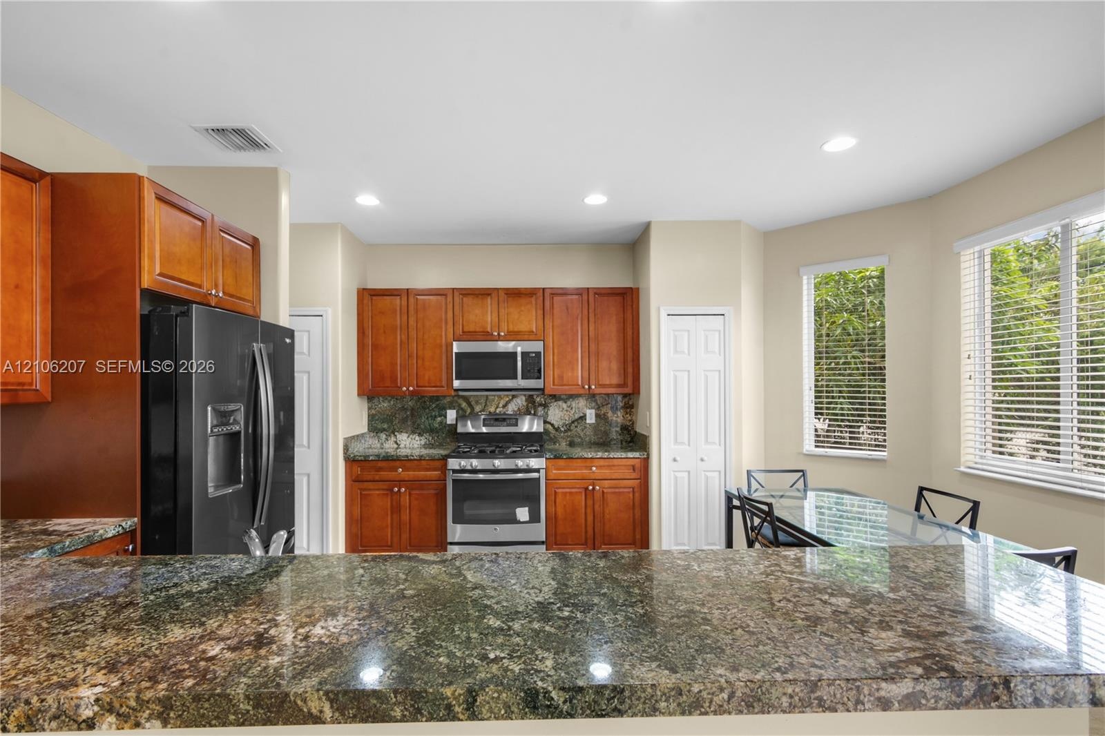 Kitchen featuring stained wood cabinetry, stone-surface breakfast bar, stainless steel appliances, and natural lighting
