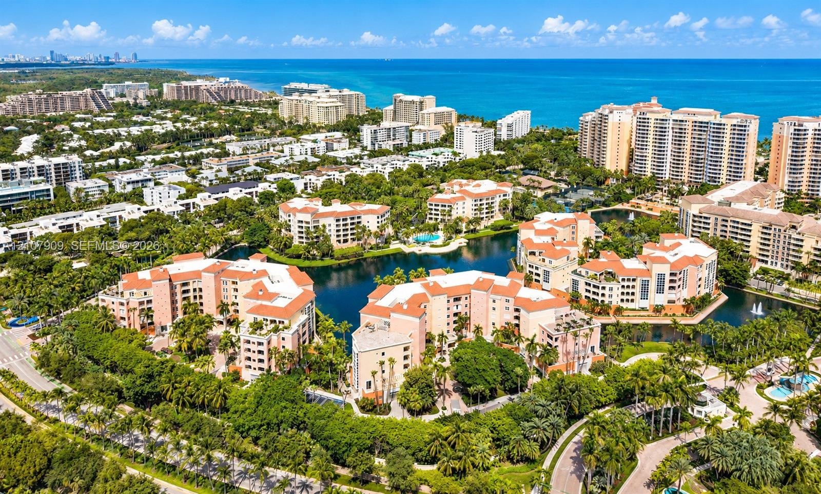 Aerial perspective of coastal residential structures featuring clay-tiled roofs, integrated water features, mature tropical landscaping, and proximity