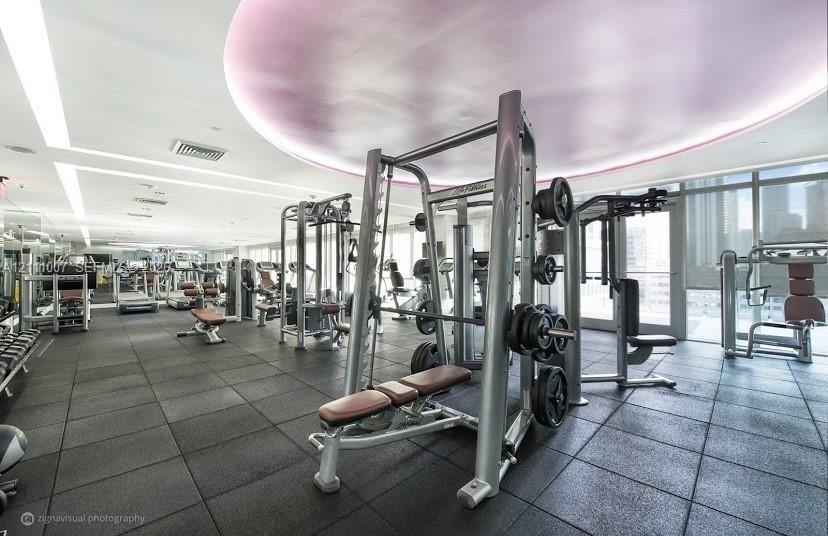 Fitness area featuring rubberized flooring, recessed architectural ceiling lighting, floor-to-ceiling windows, and multiple built-in strength training