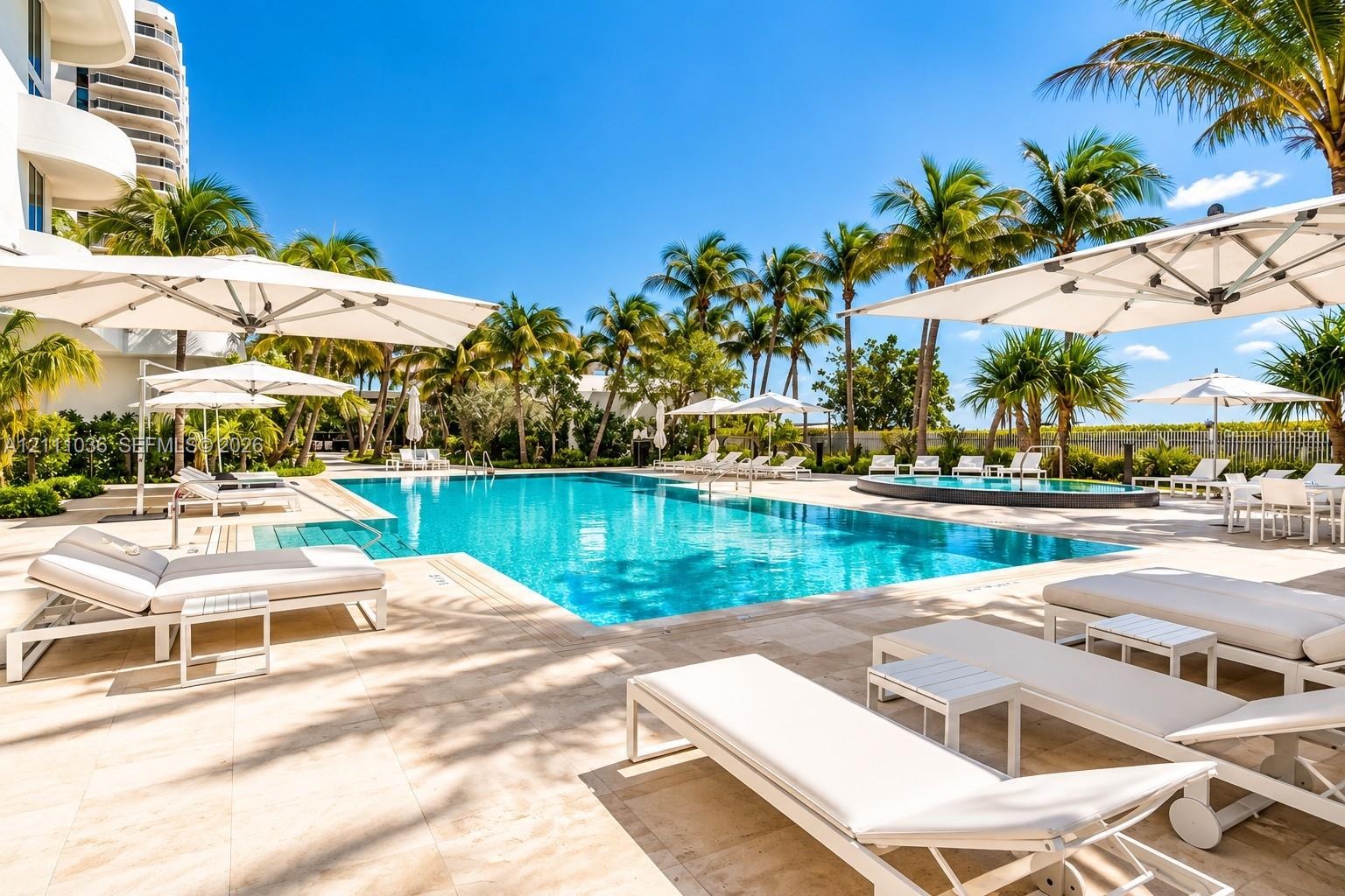 Rectangular swimming pool with stone-tiled decking, integrated spa, and mature palm trees