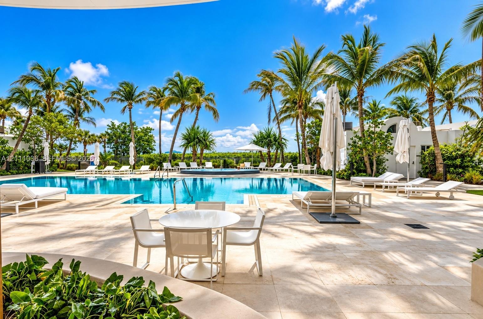 Swimming pool with integrated spa, expansive stone-paved deck, and mature palm trees