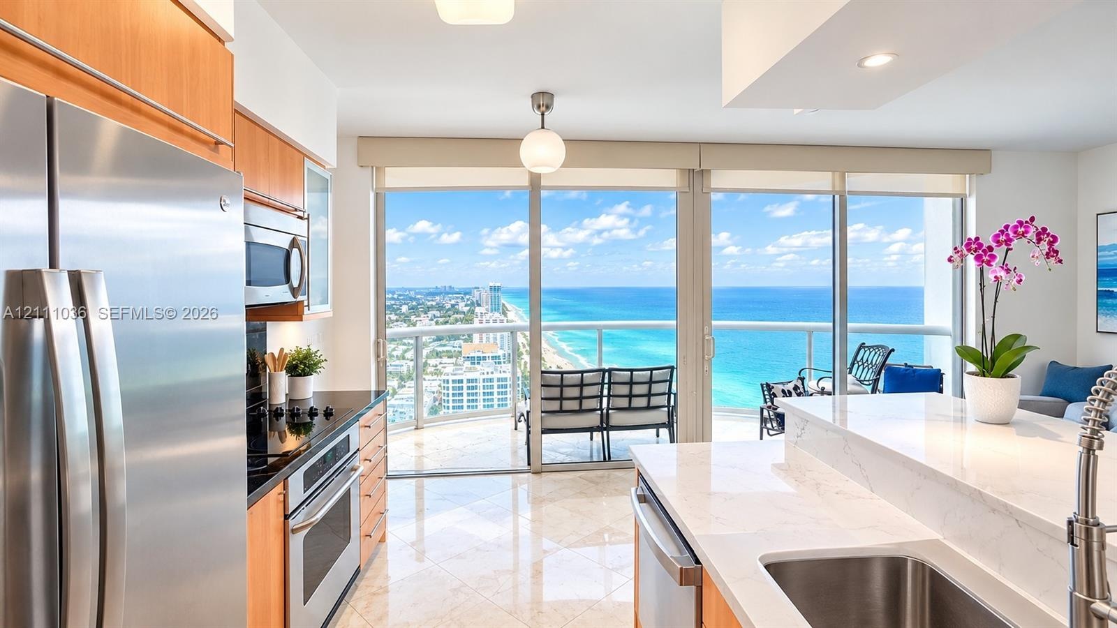 Kitchen featuring light-finish cabinetry, stone countertops, stainless steel appliances, polished tile flooring, and floor-to-ceiling glass doors open