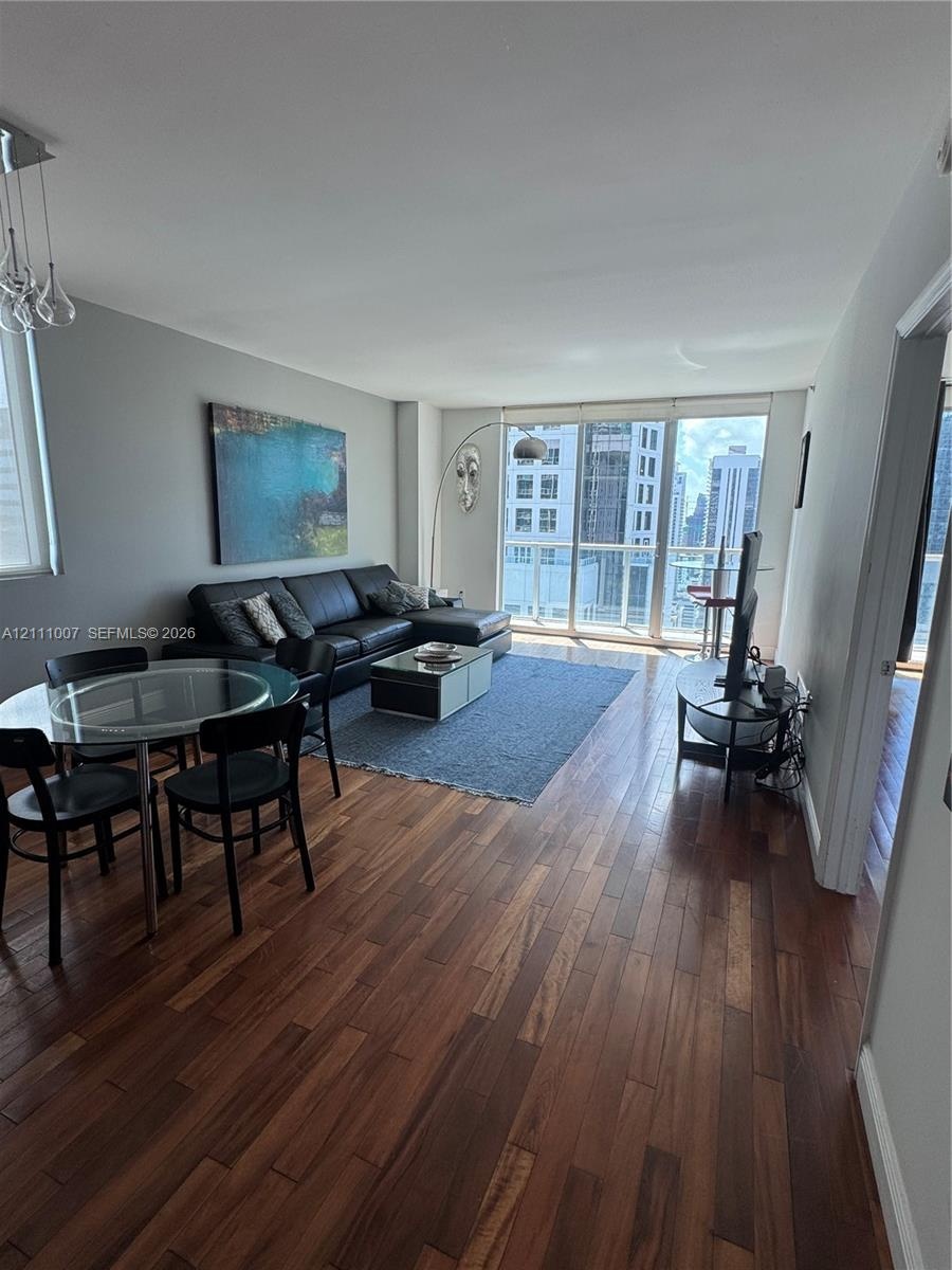 Wood-finish flooring throughout, floor-to-ceiling windows, and private balcony access