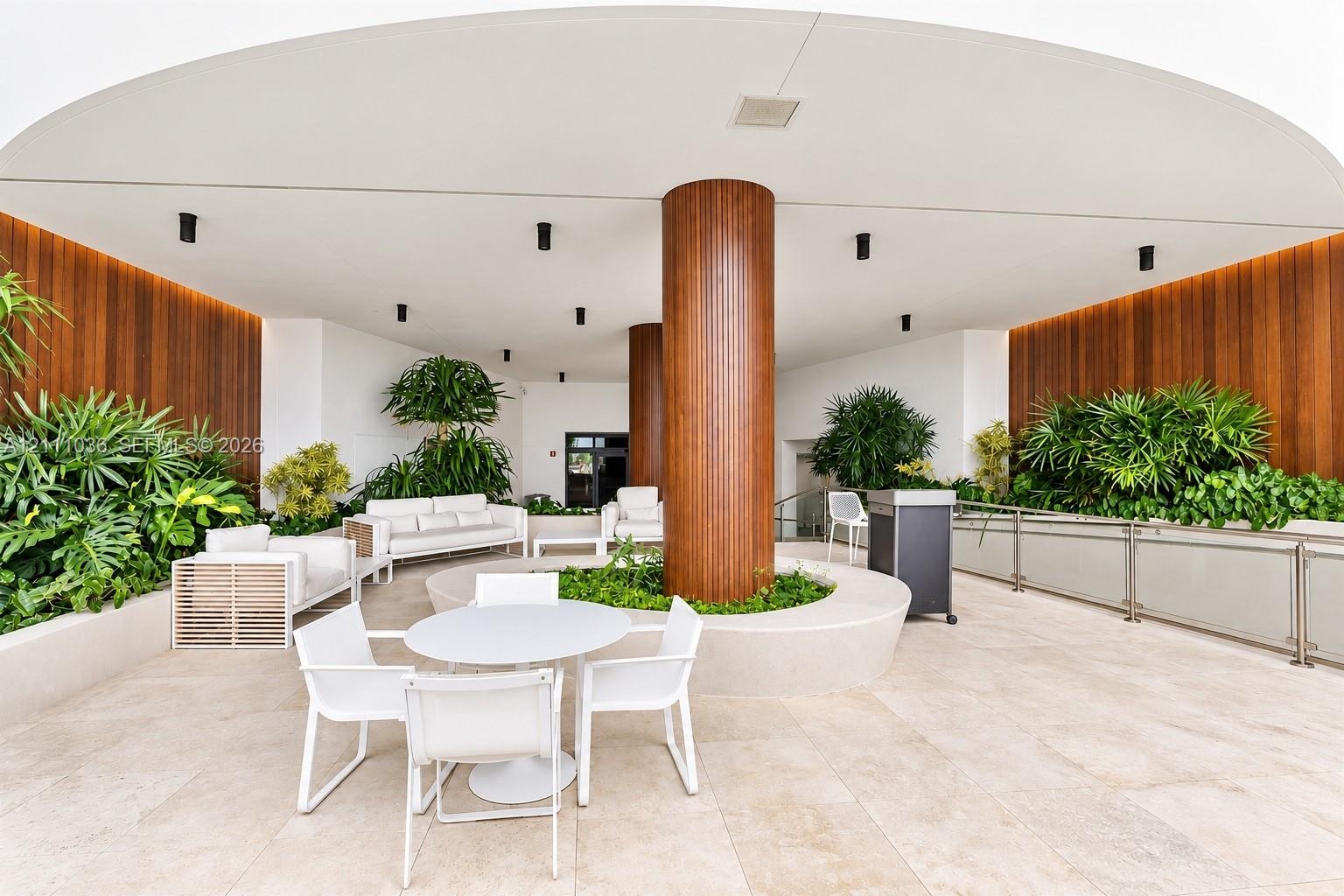 Covered outdoor terrace featuring large-format stone tile flooring, warm wood-paneled walls, integrated recessed lighting, and a central structural co