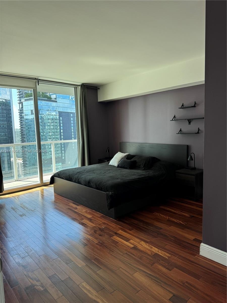 Floor-to-ceiling glass sliding doors, wood-finish flooring, and built-in wall shelving