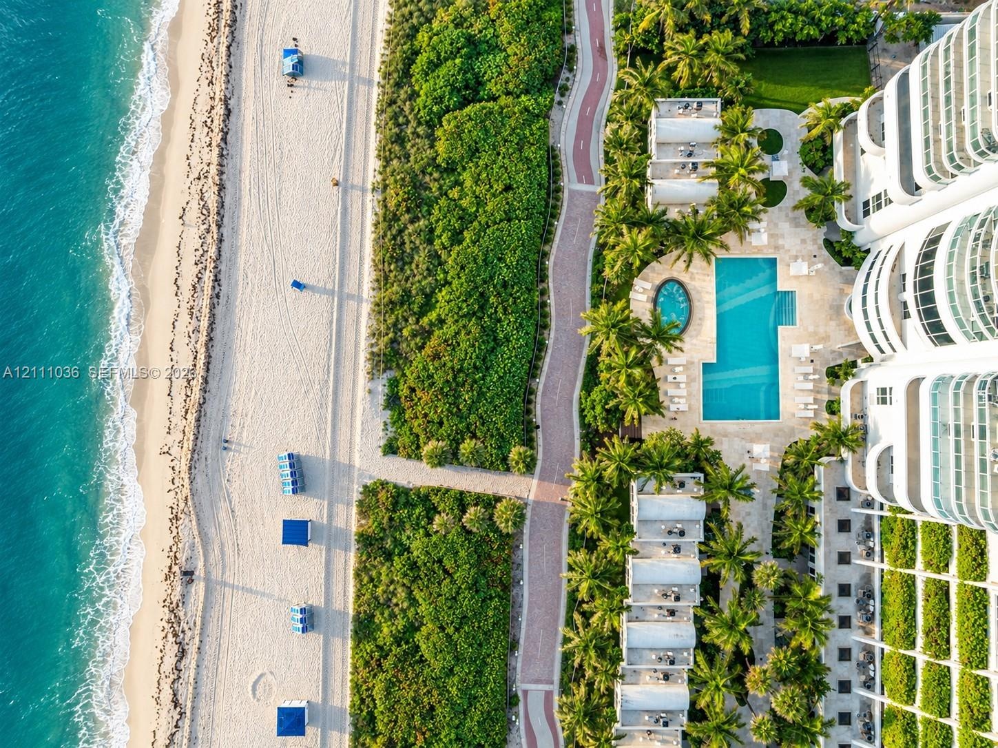 Oceanfront property featuring direct beach access, a rectangular swimming pool, a separate circular spa, paved pedestrian pathways, and lush tropical 