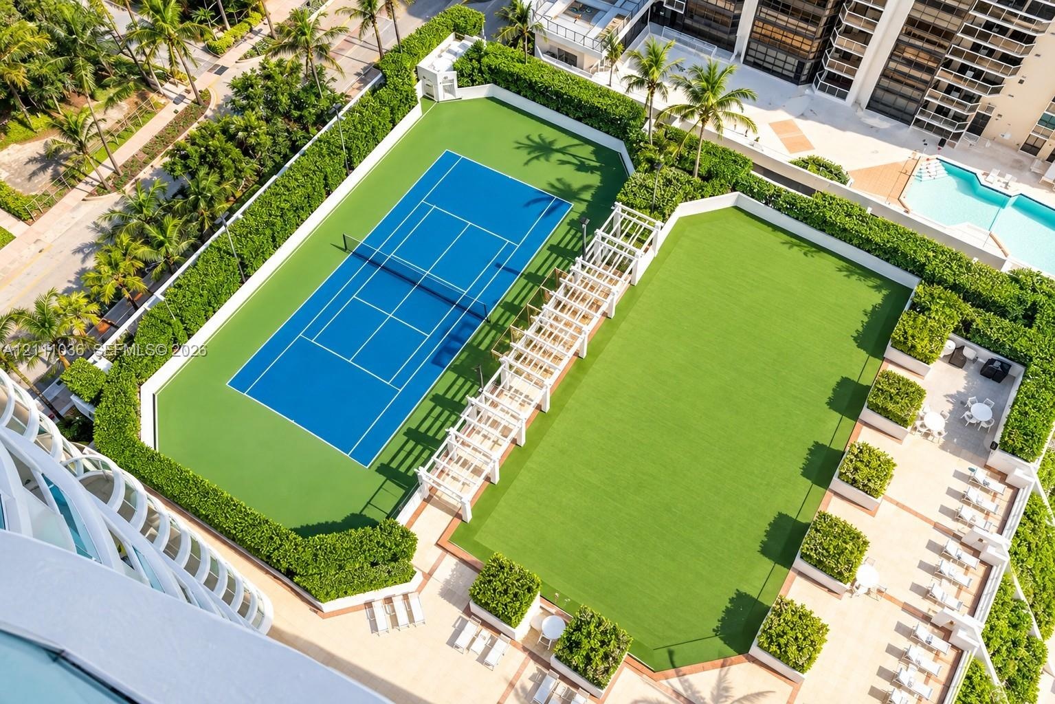 Tennis court, expansive synthetic turf lawn, white pergola structure, and landscaped privacy hedging
