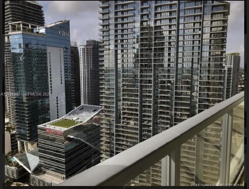 Private balcony featuring a glass panel railing and metal handrail
