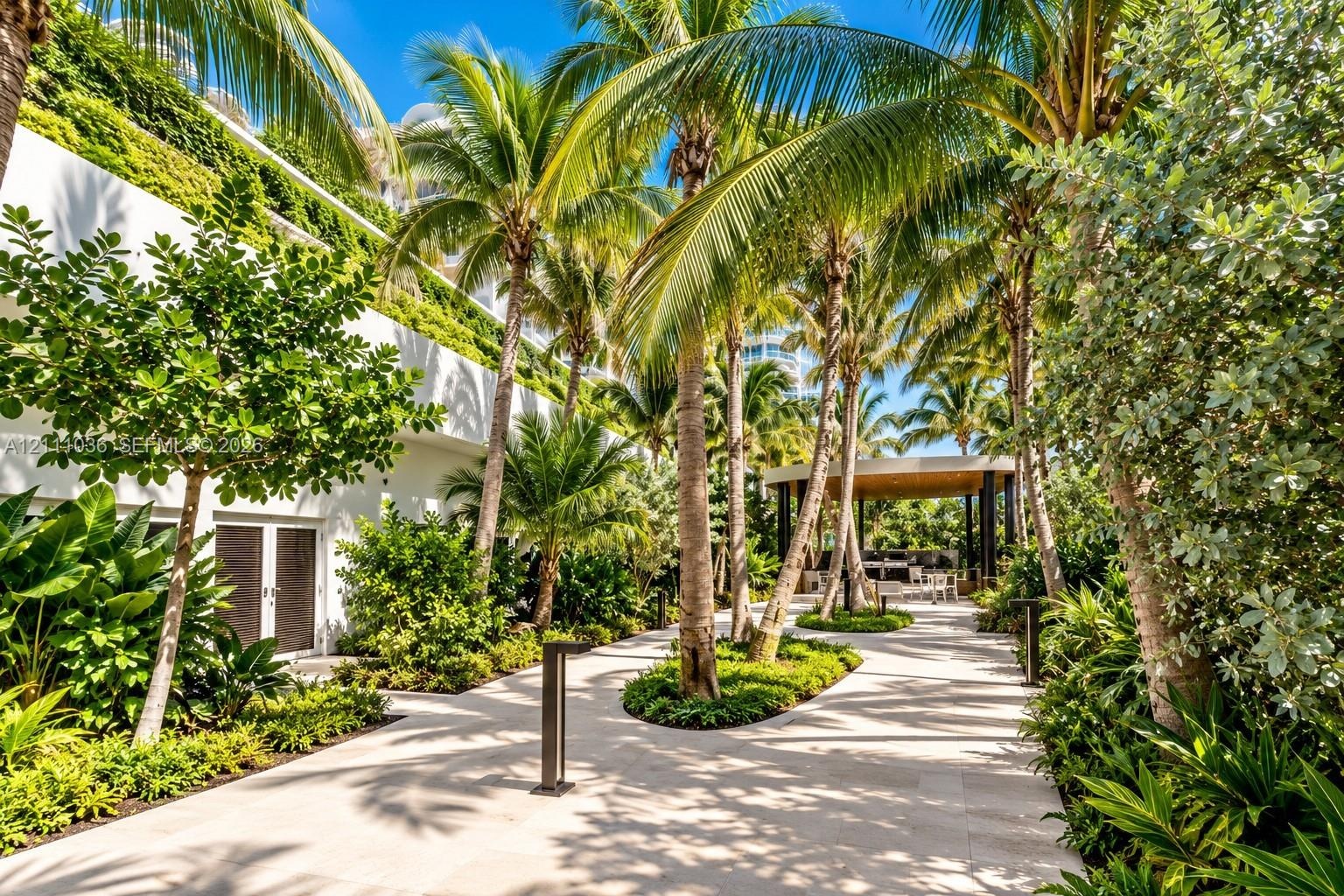 Landscaped courtyard featuring stone paving, mature palm trees, integrated green walls, and a covered pavilion