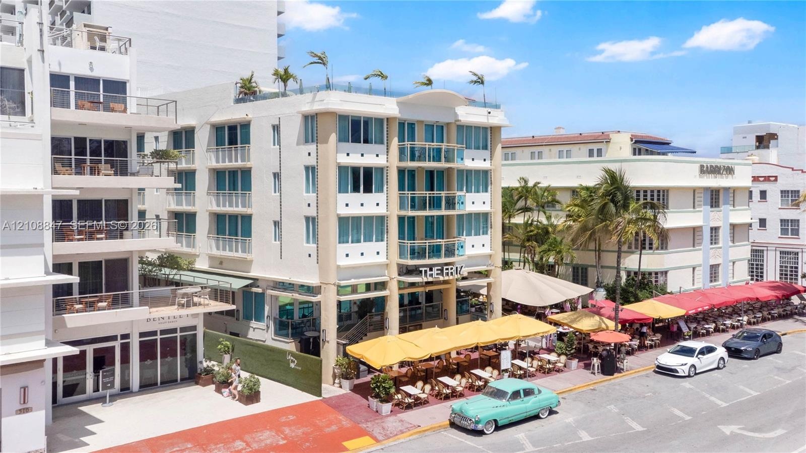 Multi-story building exterior featuring a reinforced concrete facade, integrated glass-railing balconies, floor-to-ceiling windows, and a rooftop terr
