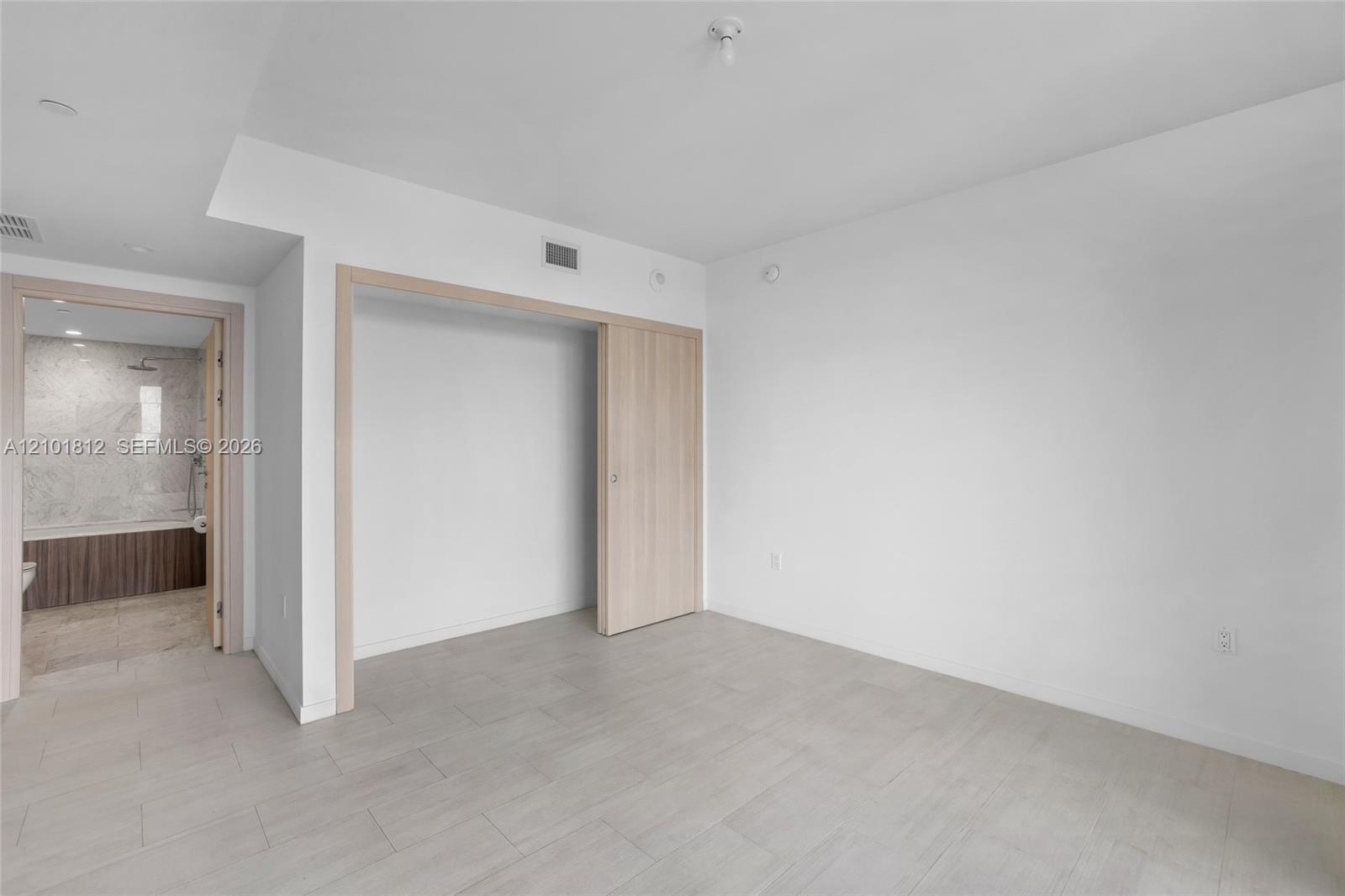 Neutral-toned tile flooring, light wood-finish sliding closet door, and crisp white wall palette