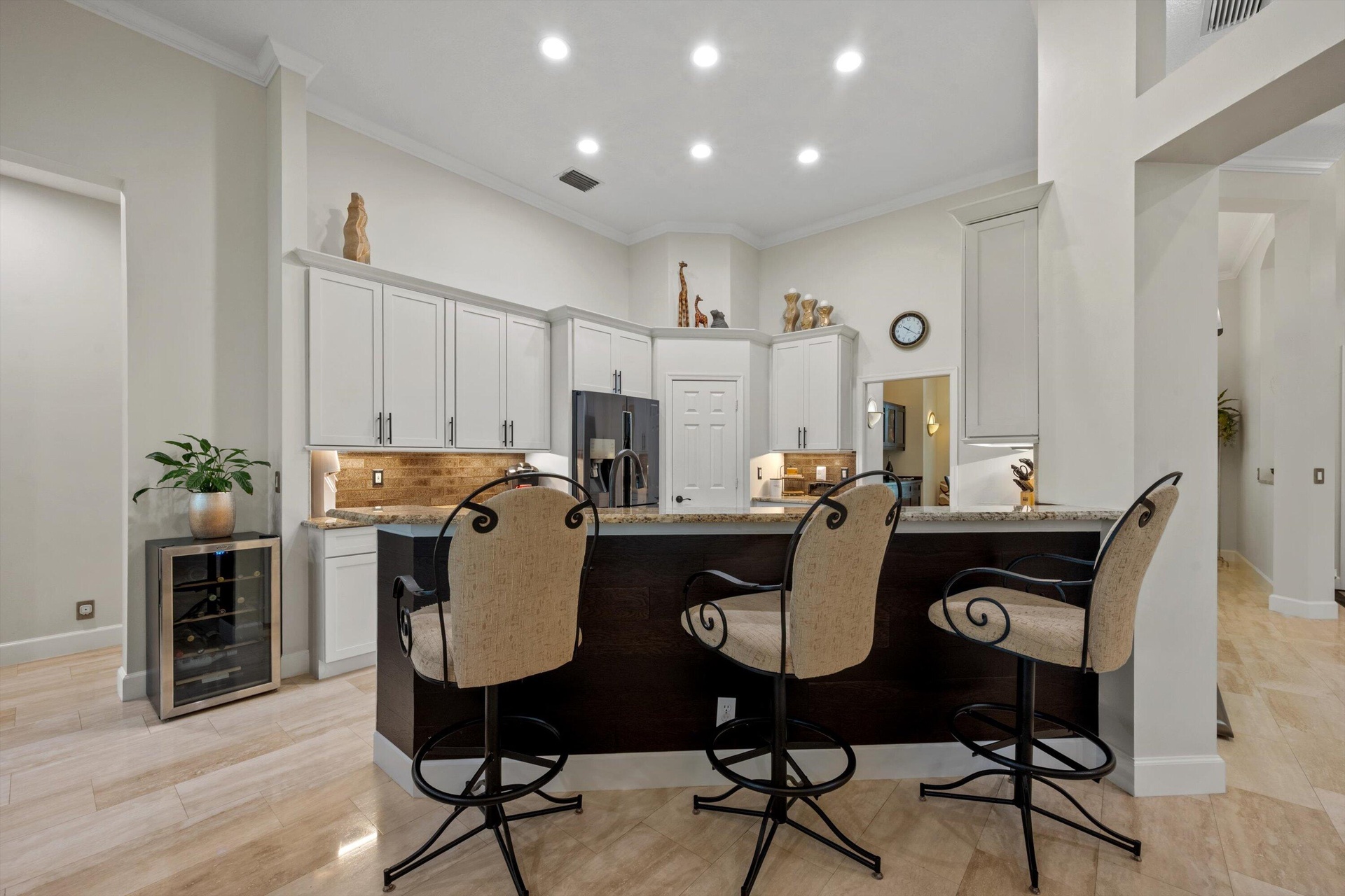 Kitchen featuring white cabinetry, stone countertops, a tile backsplash, recessed lighting, and a dark-finish peninsula with breakfast bar seating