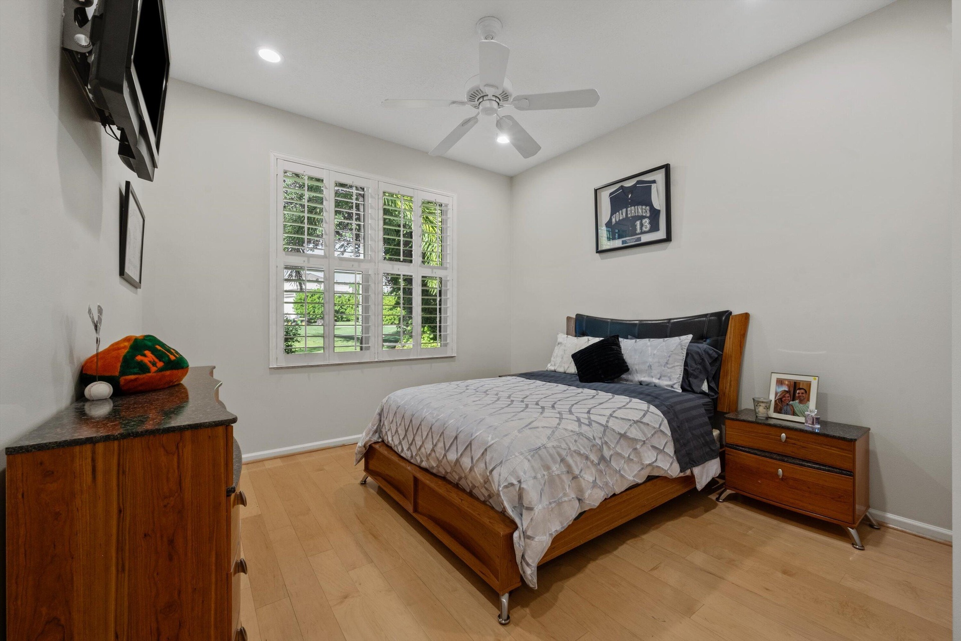 Room featuring wood-finish flooring, plantation shutters, and a ceiling fan with integrated lighting