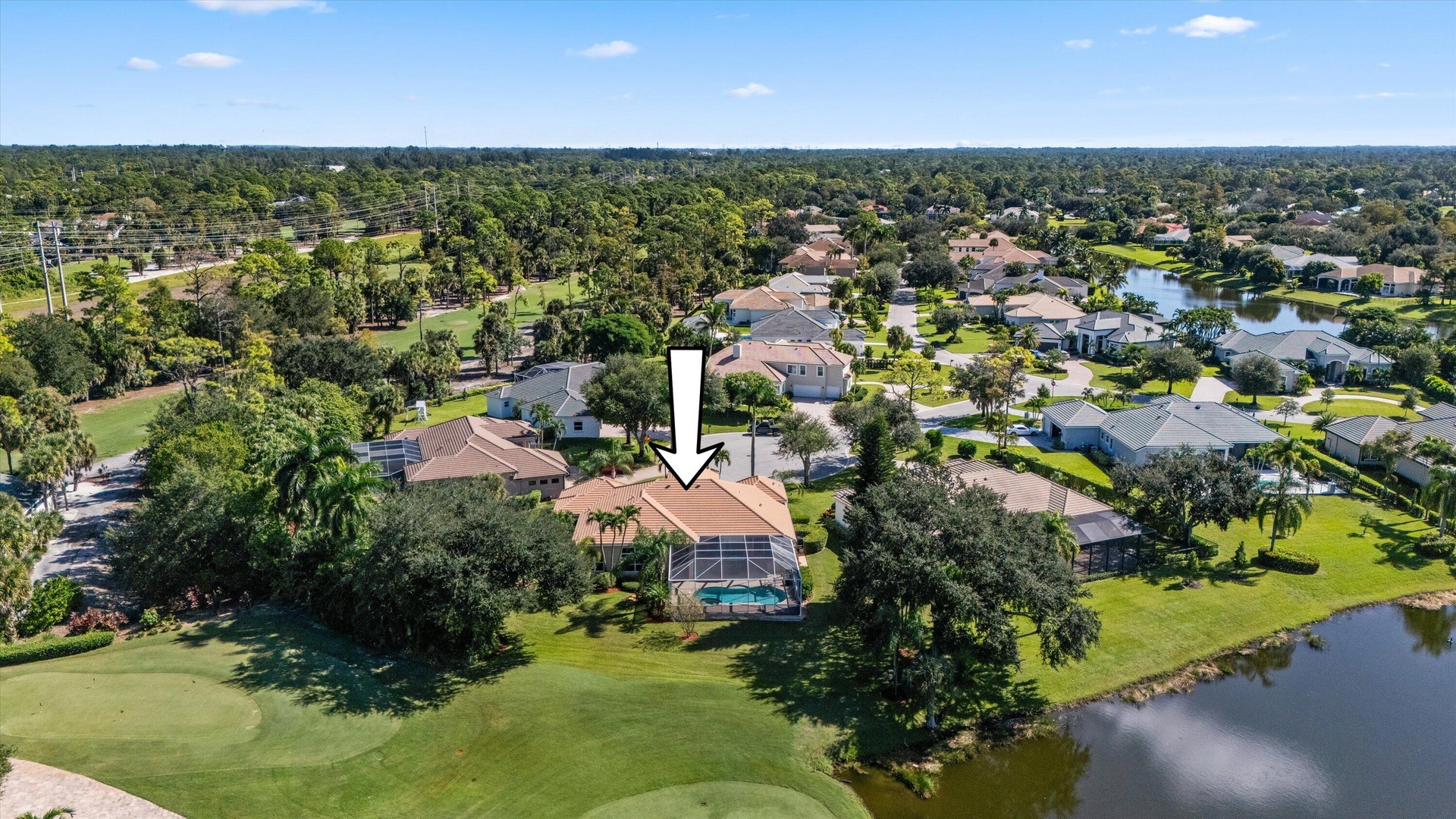 Aerial perspective of residence featuring a tile roof, screened-in swimming pool enclosure, and direct positioning on a golf course