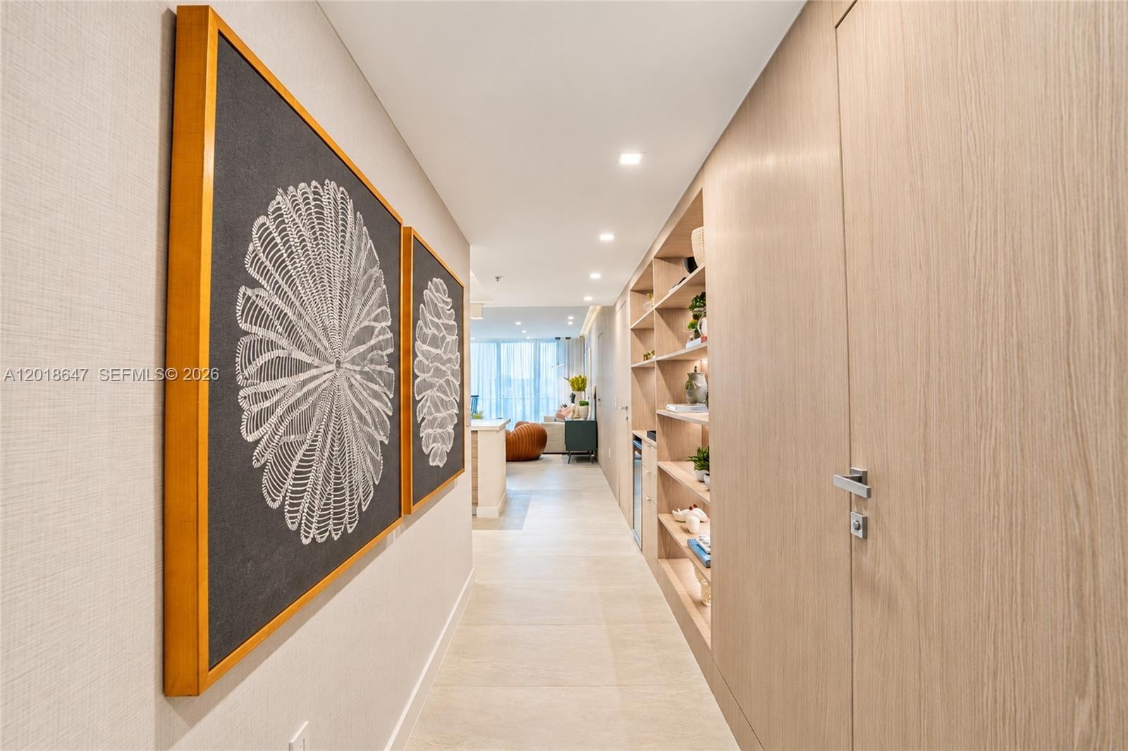 Living area featuring floor-to-ceiling glass sliding doors, textured accent wall, built-in cabinetry with integrated shelving, recessed ceiling lighti