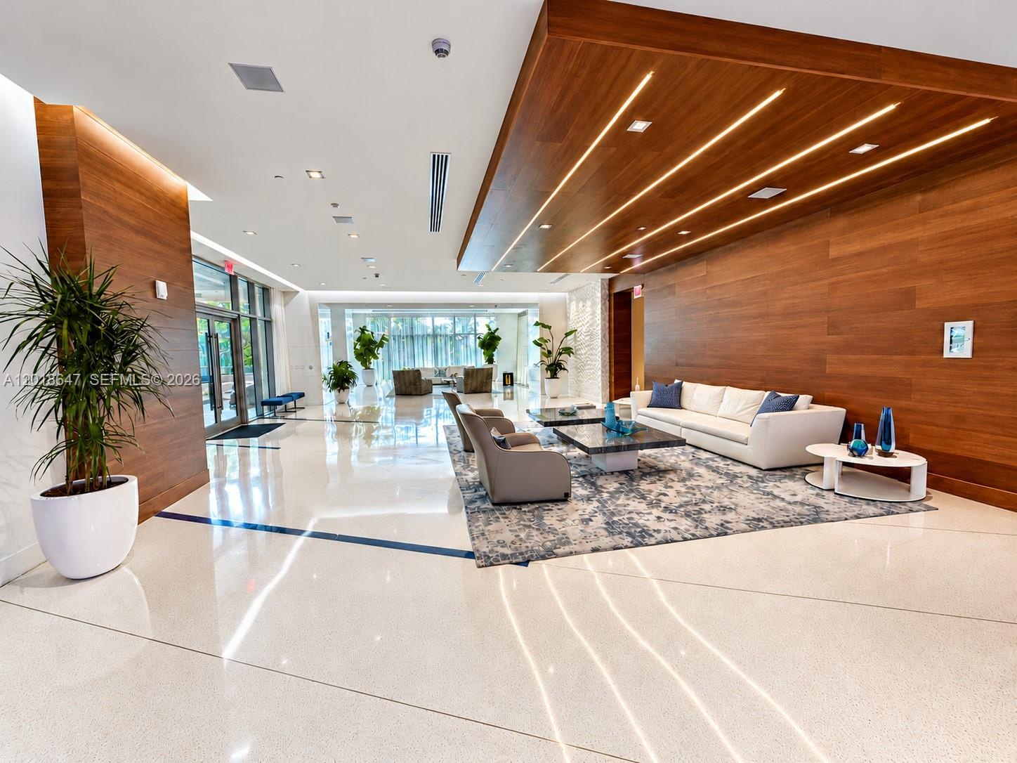 Hallway featuring tile flooring, textured wall covering, recessed lighting, and a wall of integrated wood-finish cabinetry with built-in shelving