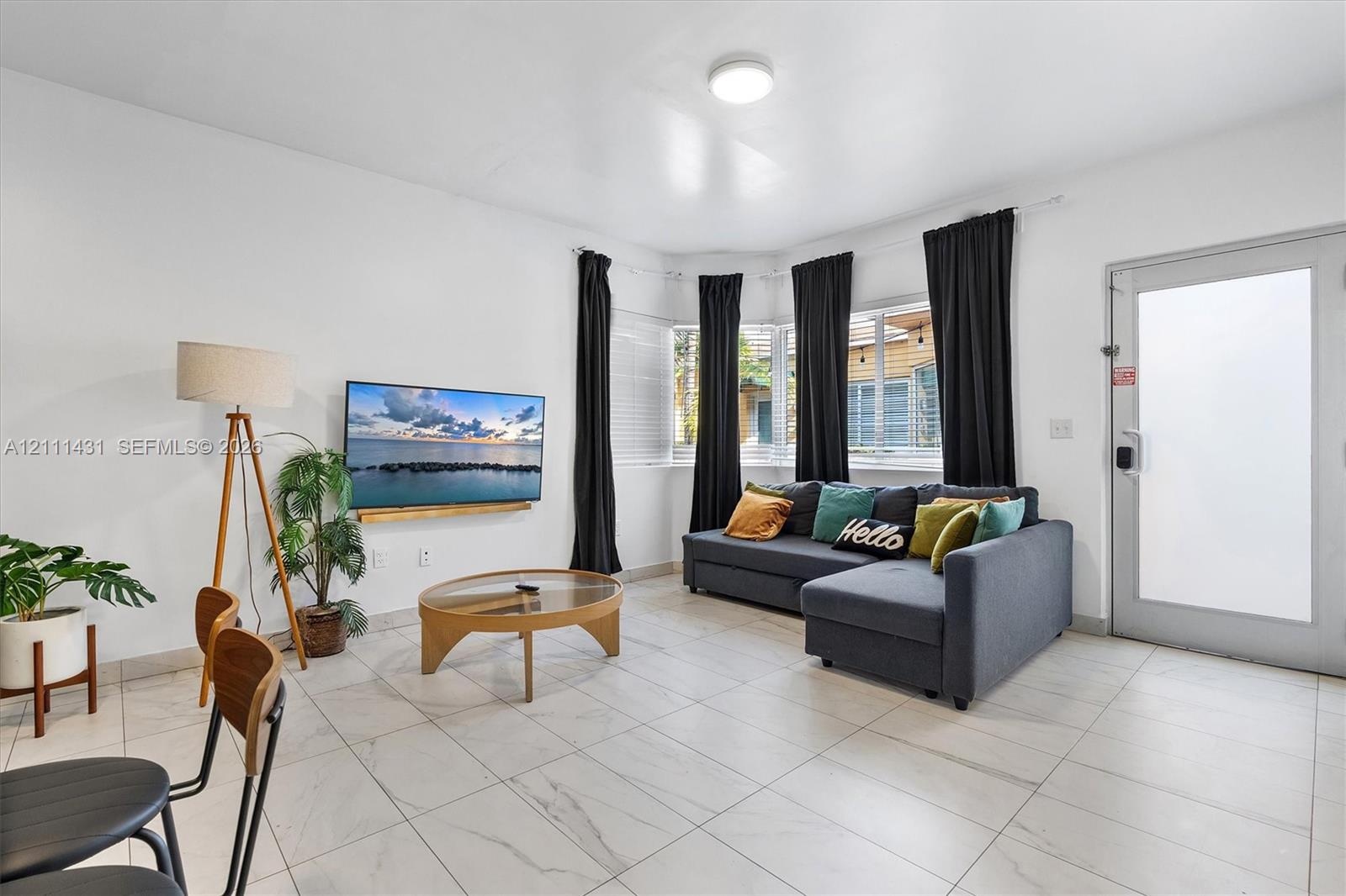 Living space featuring large-format tile flooring, a recessed bay window, flush-mount ceiling lighting, and a glass-paneled exterior door