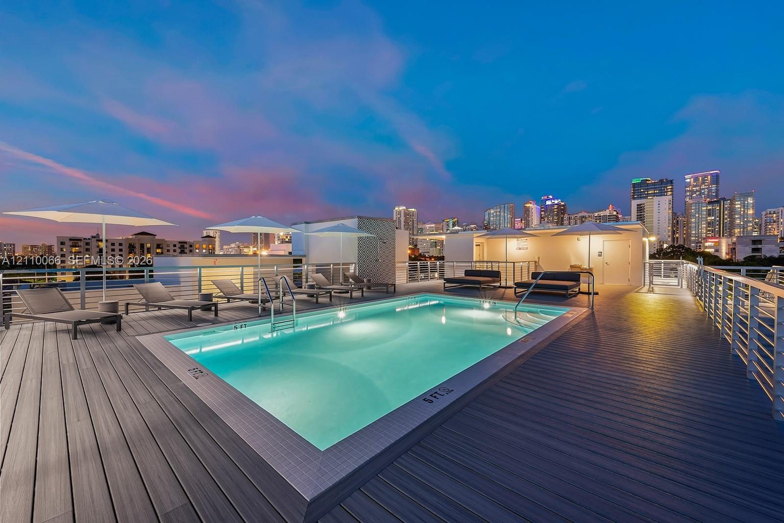 Rooftop pool with tile surround, composite decking, and metal railing enclosure