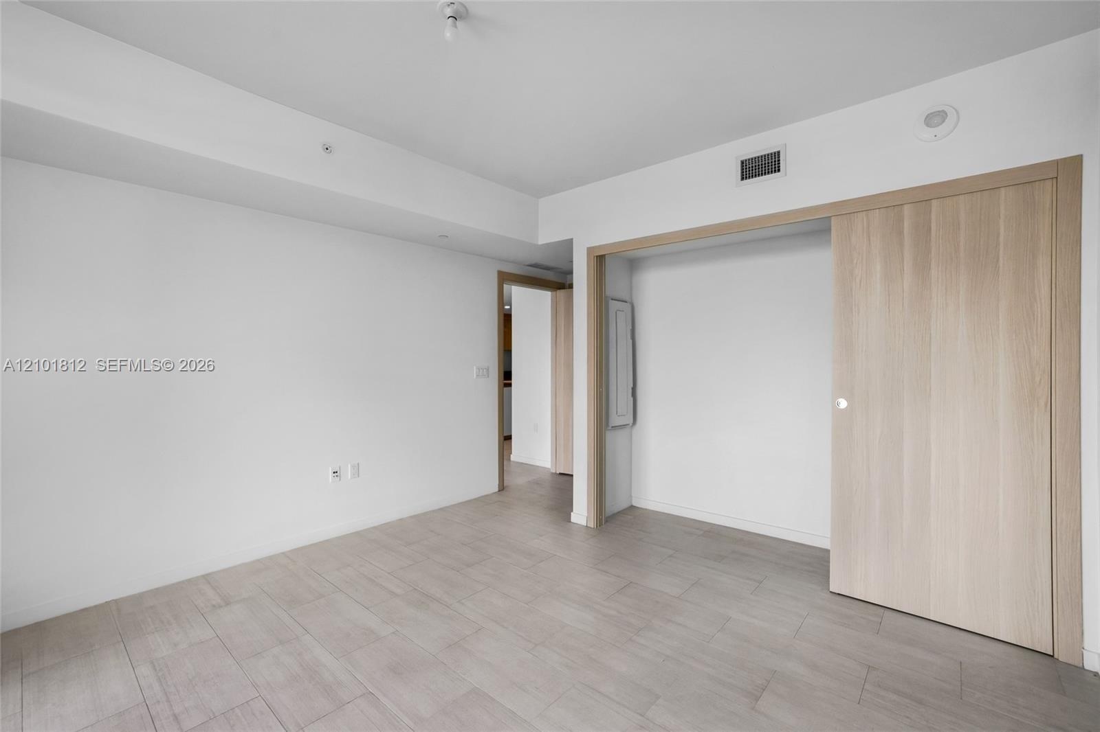 Neutral-toned ceramic tile flooring, clean-lined white walls, and a light wood-finish sliding door system