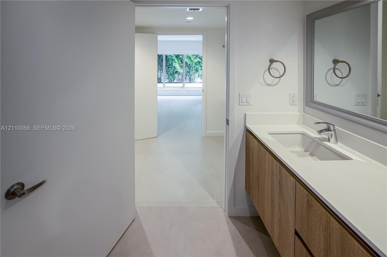 Floating wood-finish vanity with an integrated basin, smooth countertop, chrome faucet, and rectangular mirror