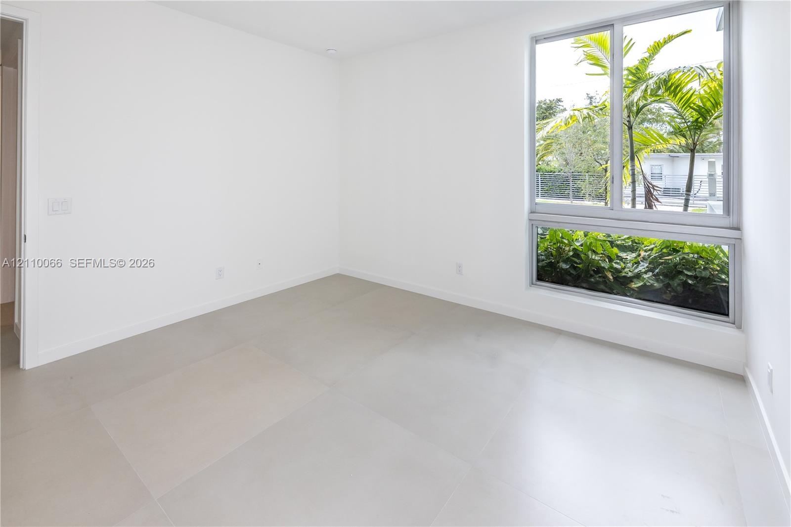 Large-format neutral tile flooring and oversized dual-pane window with metallic framing