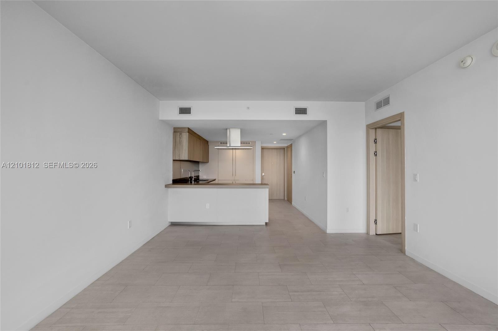 Open floor plan featuring tile flooring, neutral wall finishes, kitchen with wood-finish cabinetry, countertop breakfast bar, and stainless steel rang