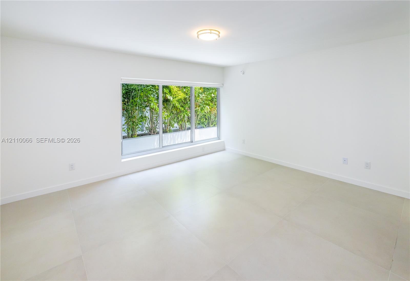 Interior space featuring large-format tile flooring, a triple-pane window system, flush-mount circular lighting, and smooth-finish white walls
