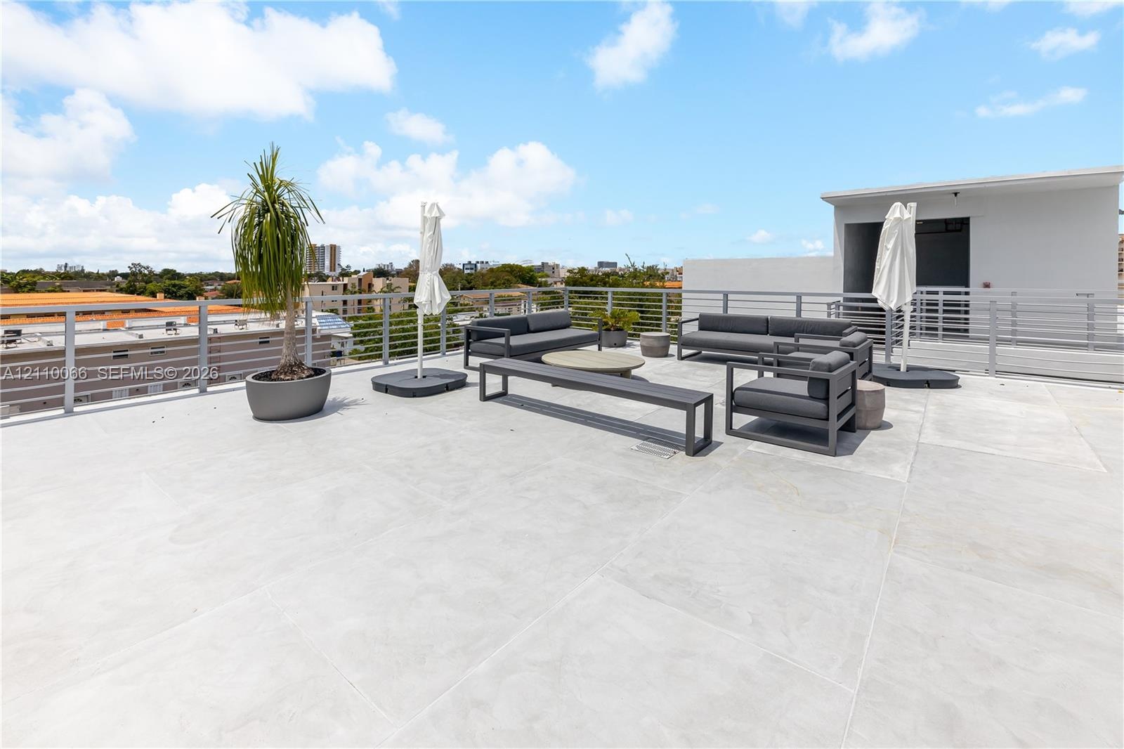 Expansive rooftop terrace featuring large-format paver tiles and metallic horizontal-slat railings