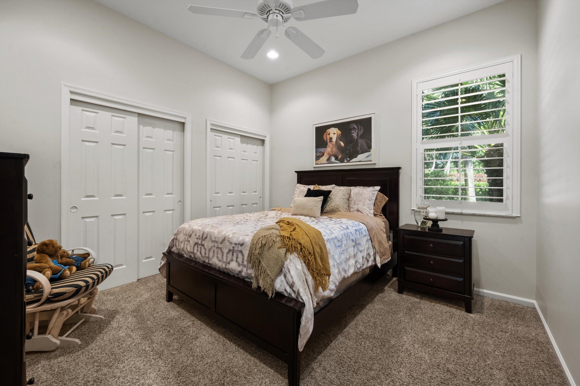 High-ceiling room featuring neutral carpeting, plantation shutter window coverings, and a ceiling-mounted fan with integrated lighting