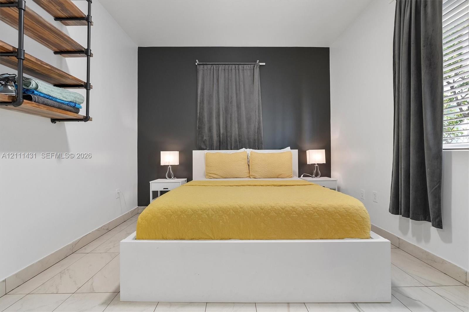 Room featuring a charcoal accent wall, tile flooring, and wall-mounted industrial-style shelving with wood-finish planks